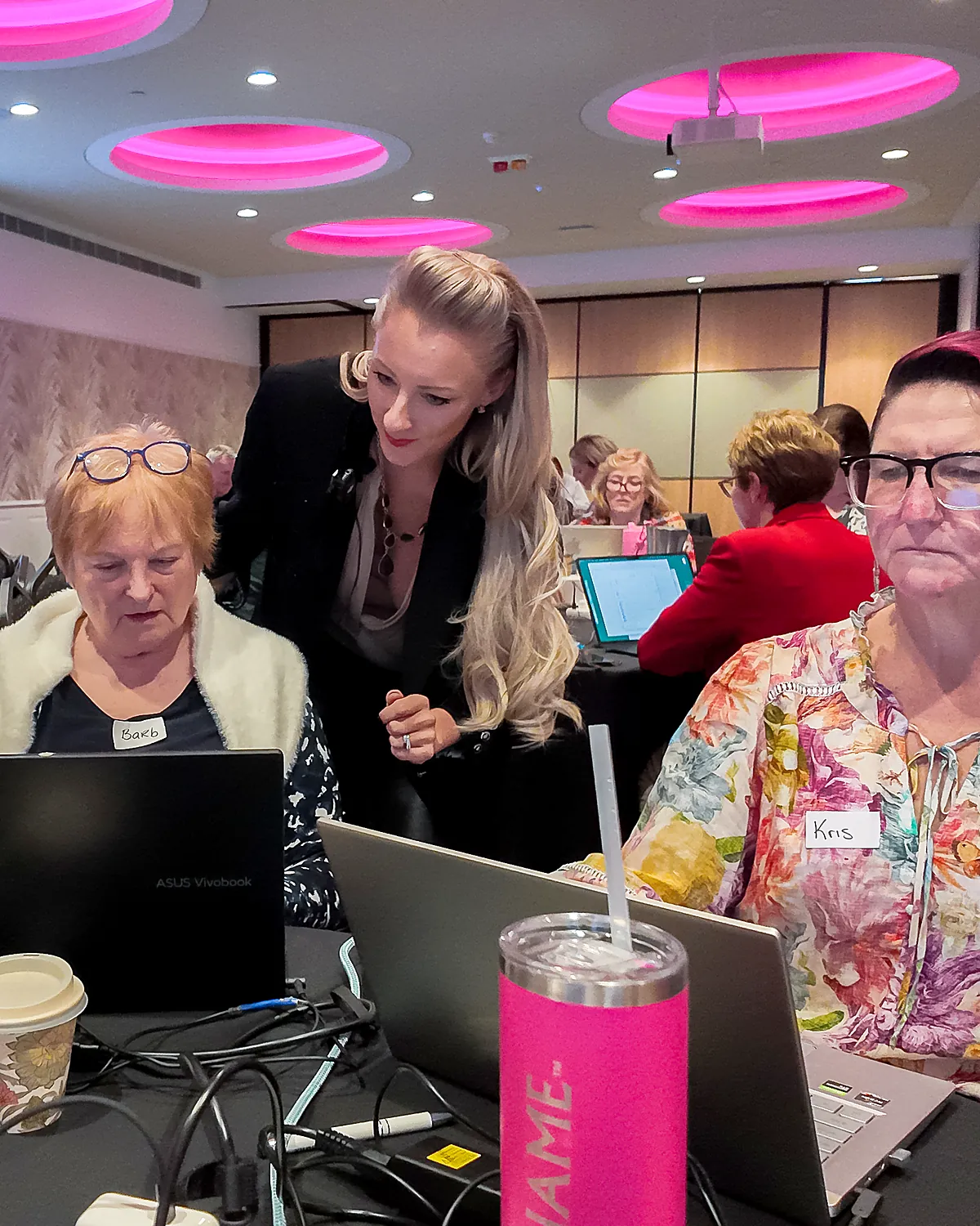 Sarah Cordiner helping two attendees at their laptops