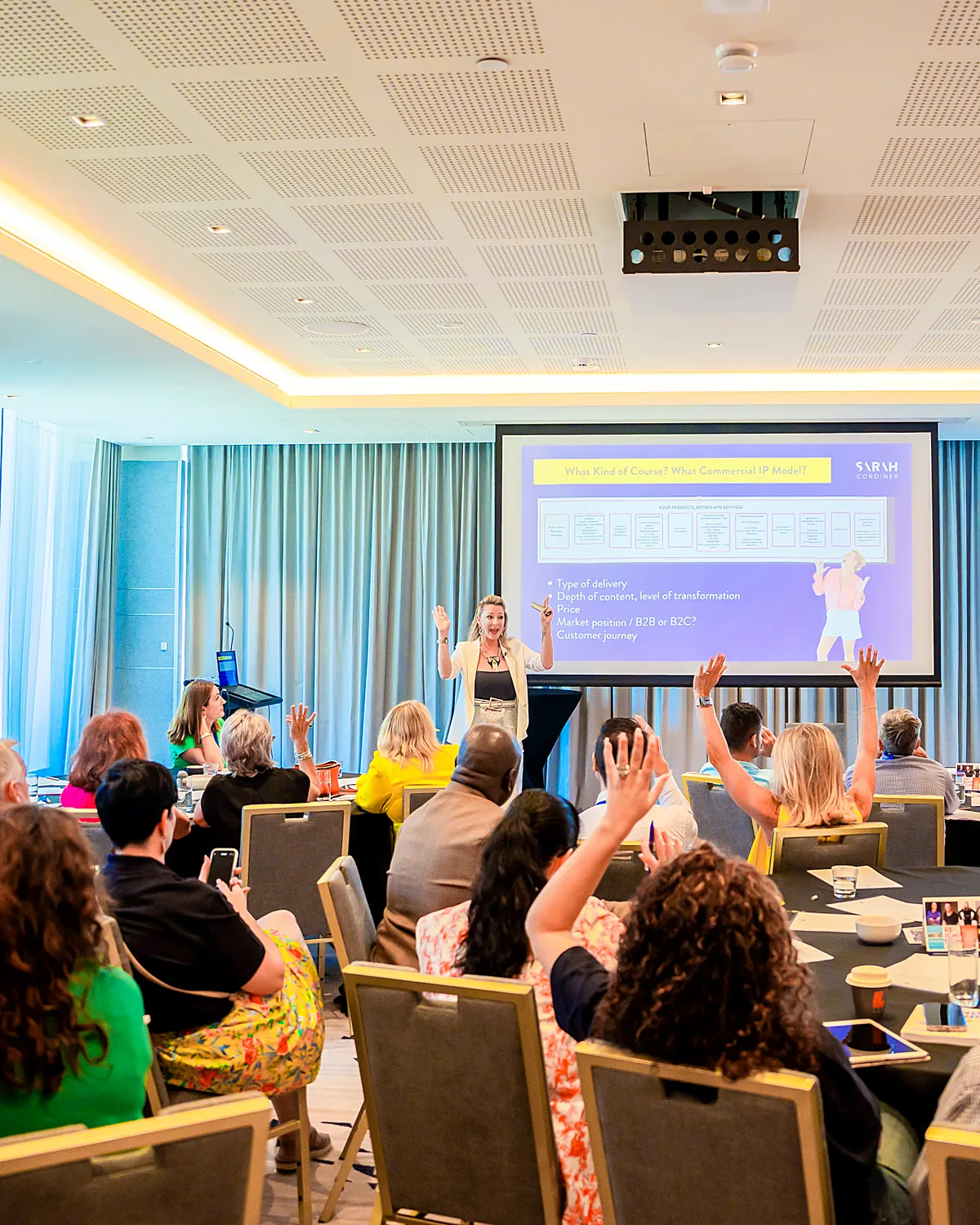 Sarah Cordiner running an interactive workshop with the audience's hands raised